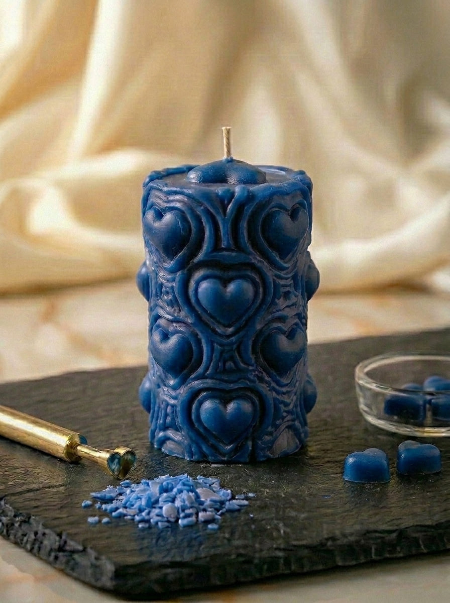 Blue decorative candle with heart patterns on a dark surface with a soft beige background