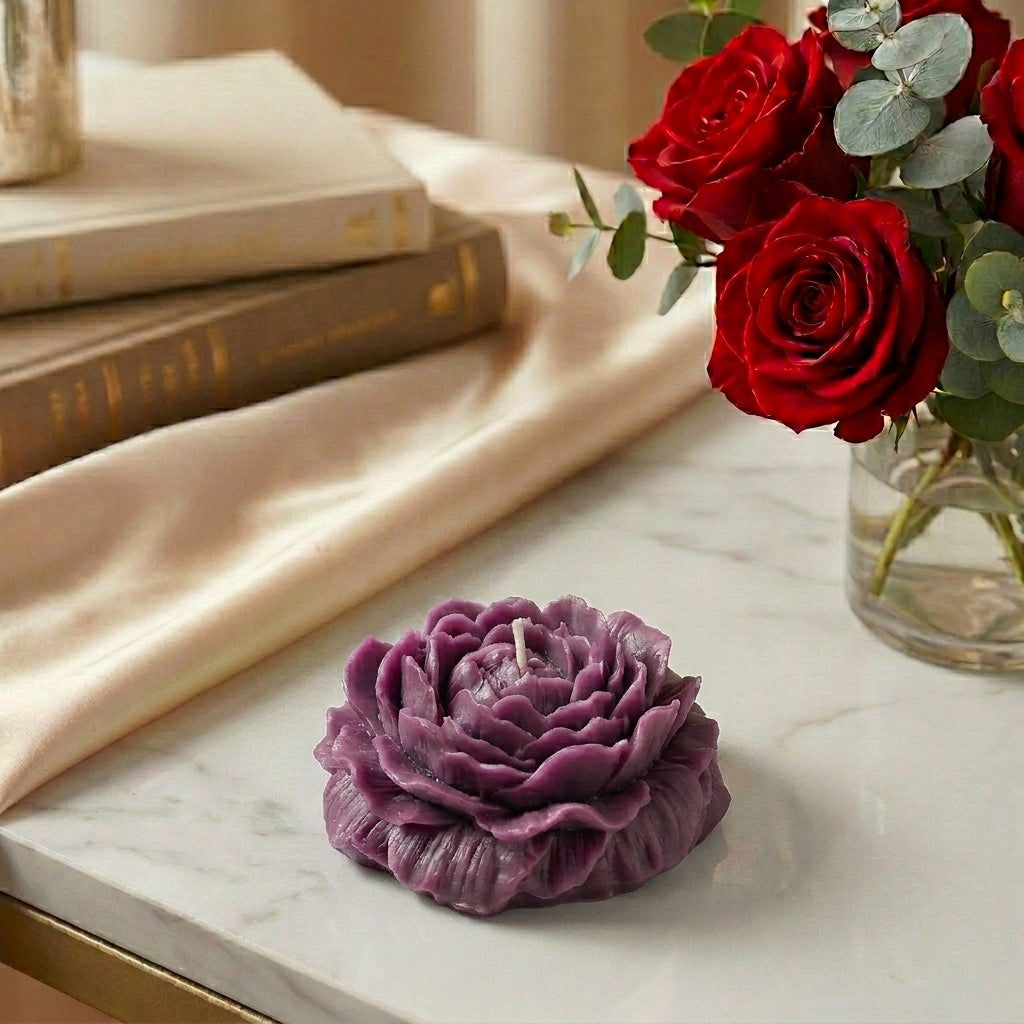 Purple flower-shaped candle on a marble surface with red roses in the background