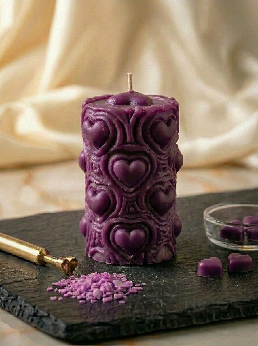 Decorative purple candle with heart patterns on a dark surface with a soft beige background