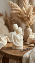 Candle shaped like a couple on a wooden table with dried plants and lavender.